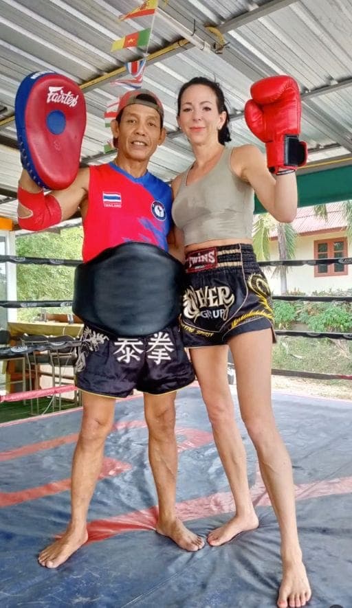 Sandra mit Boxhandschuhen neben ihrem thailändischen Trainer im Ring