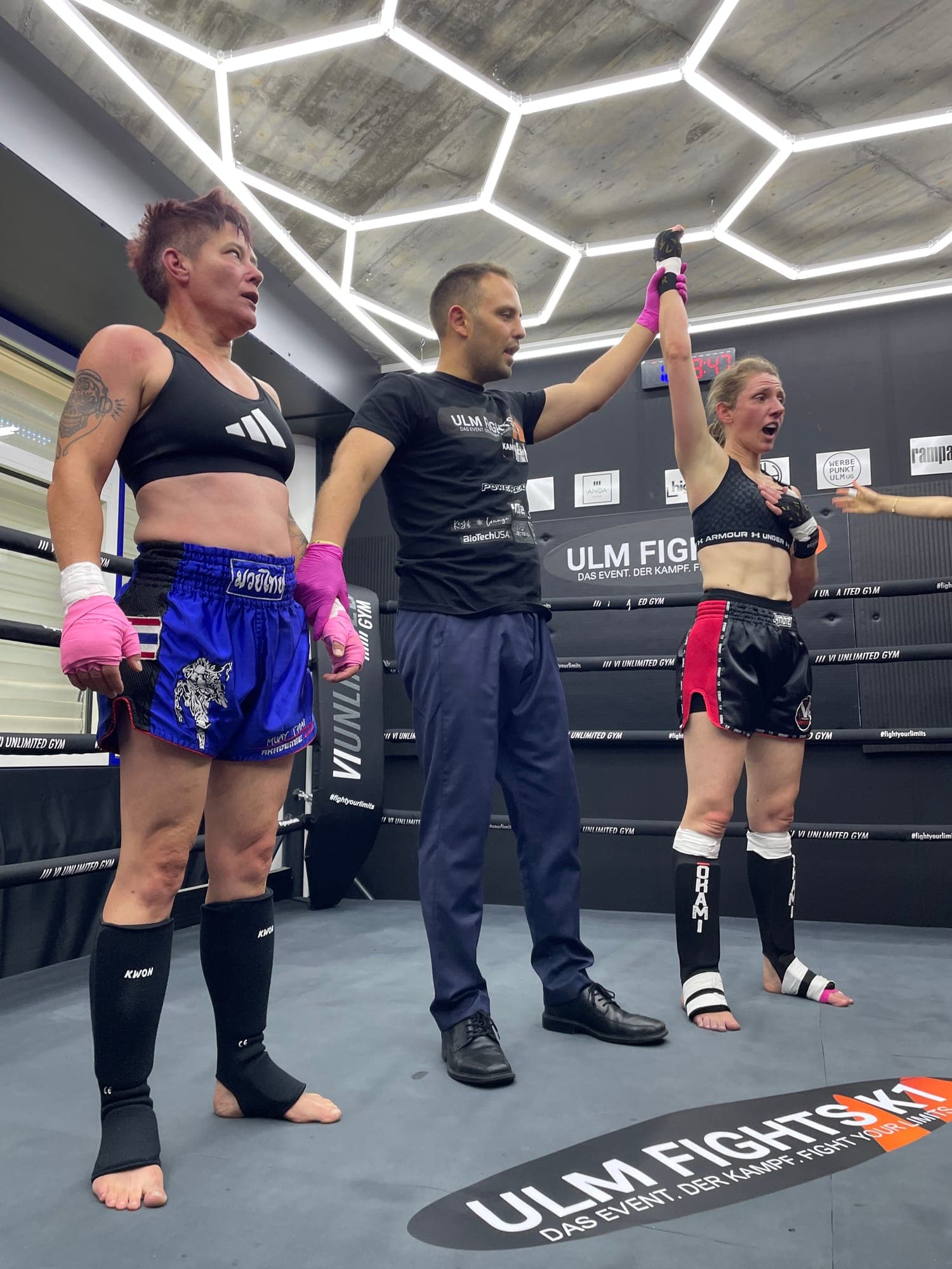 Ringrichter hebt nach einem Muay-Thai-Kampf den Arm einer Kämpferin